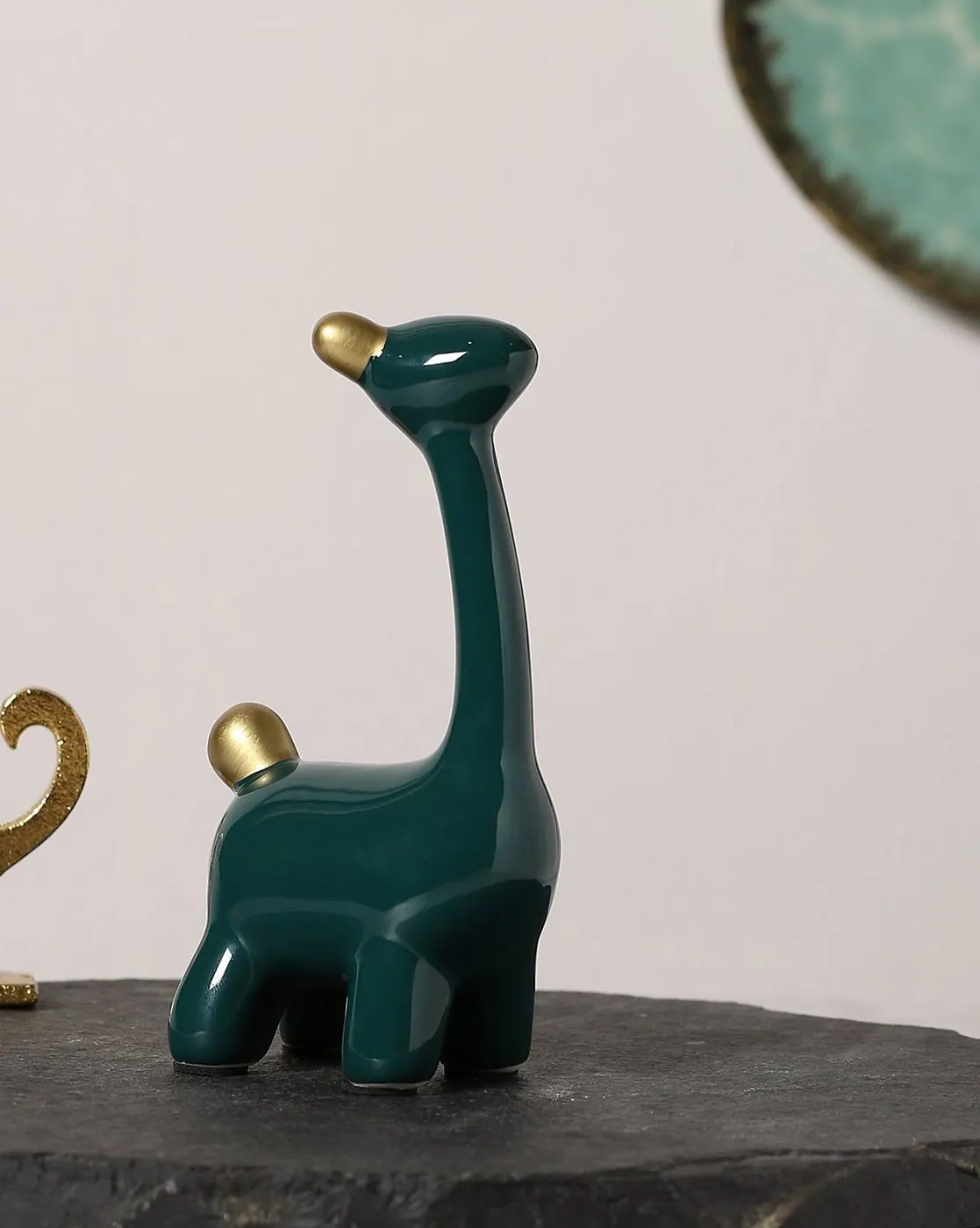 A glossy forest-green ceramic giraffe figure with gold accents