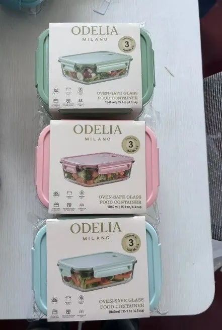 Three ODELIA Milano glass food containers in sage, pink and blue retail boxes