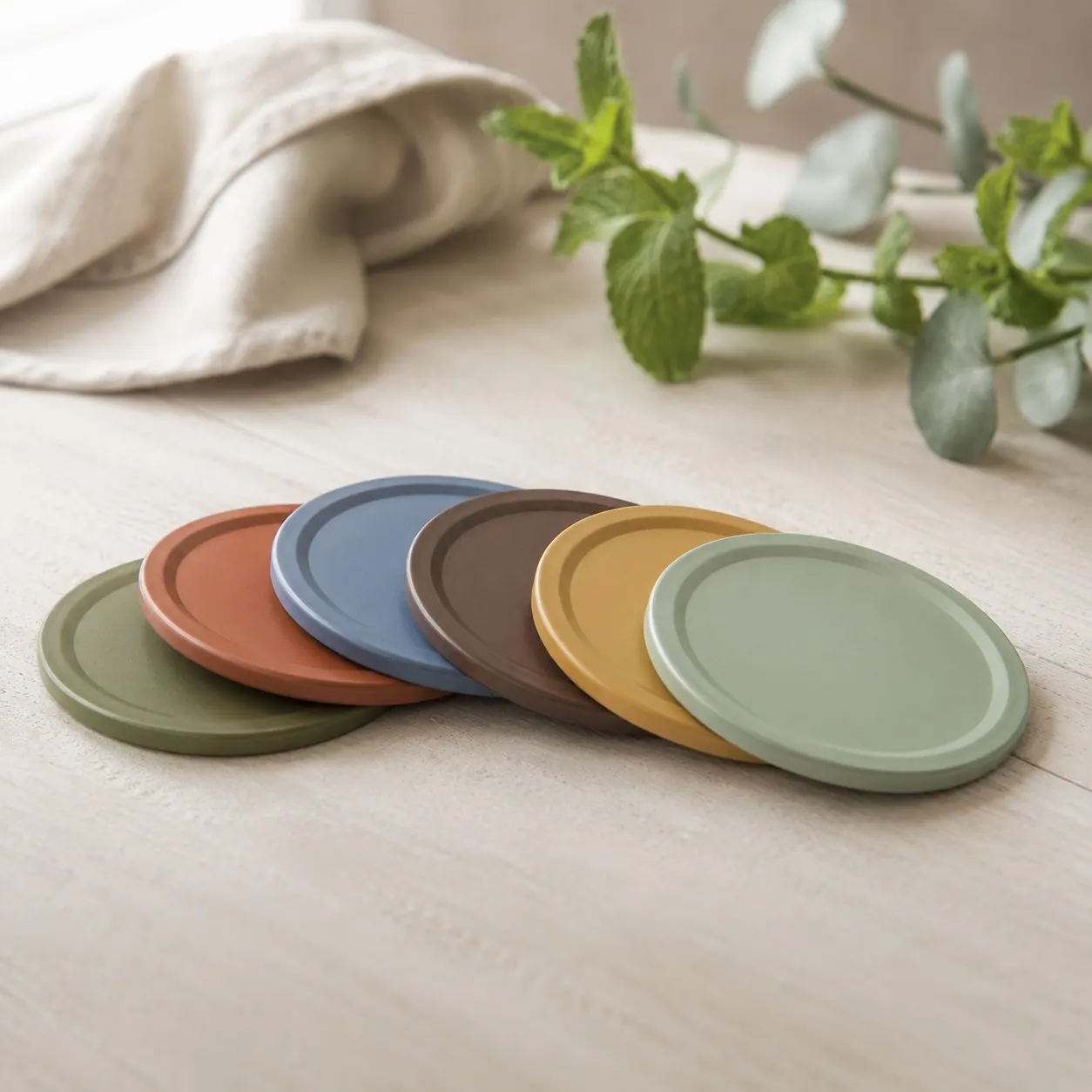 Six matte jar lids fanned out in olive, terracotta, blue, mocha, mustard and sage