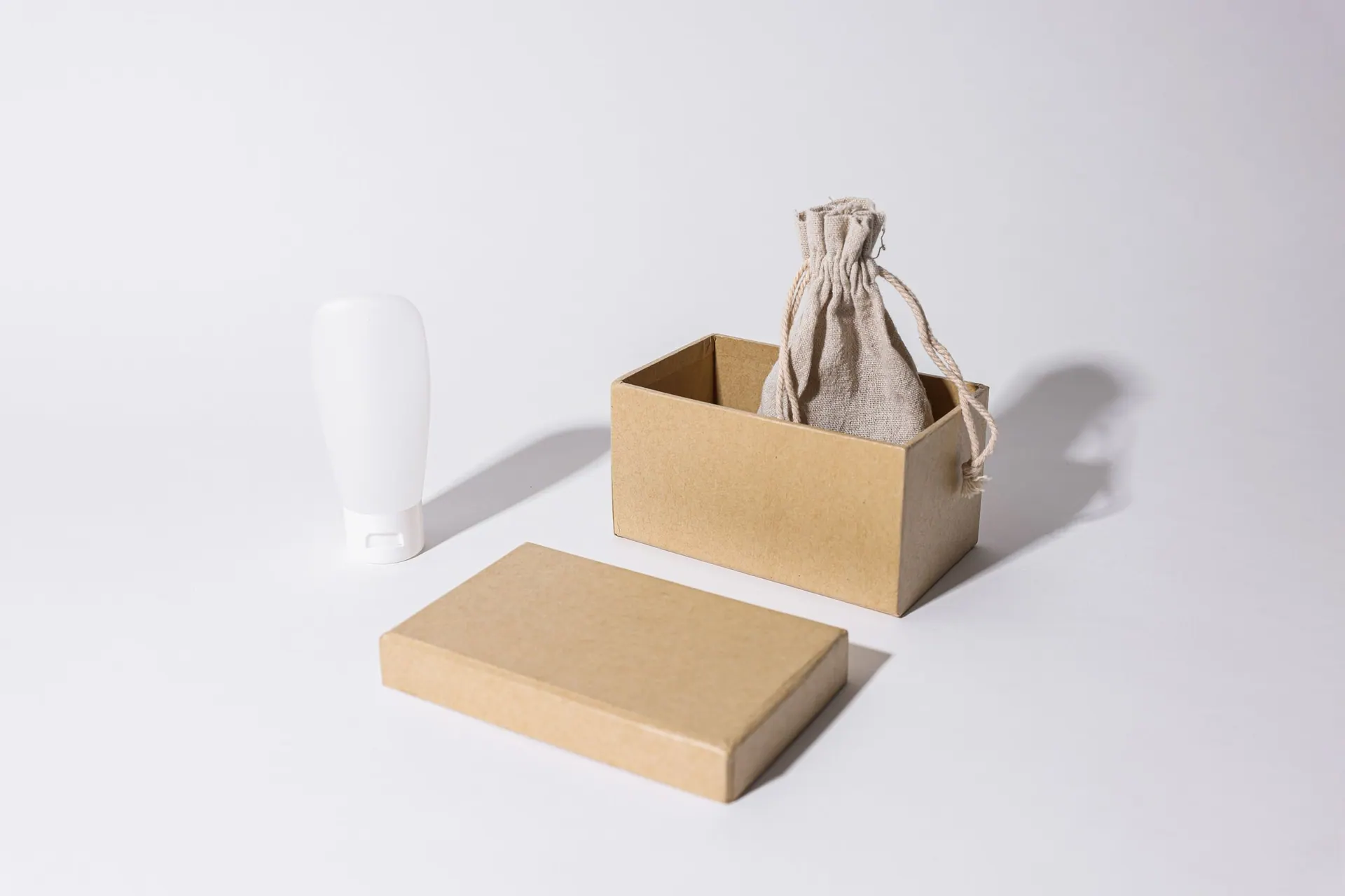 A plain kraft box, linen pouch and tube on a white set
